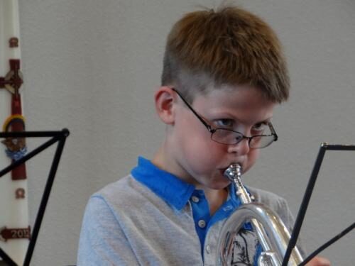 Een jonge muzikant speelt achter de lessenaar tijdens de repetitie.